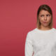 indoor-portrait-young-female-posing-red-background-looks-aside-copy-space-with-confused-irritated-facial-expression