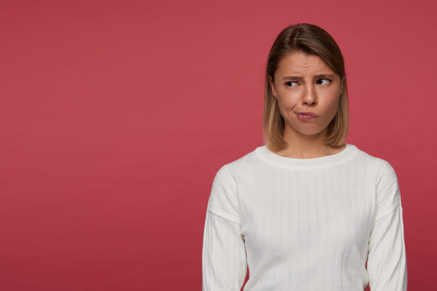 indoor-portrait-young-female-posing-red-background-looks-aside-copy-space-with-confused-irritated-facial-expression