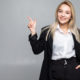 young-business-woman-pointing-finger-side-isolated-grey-wall