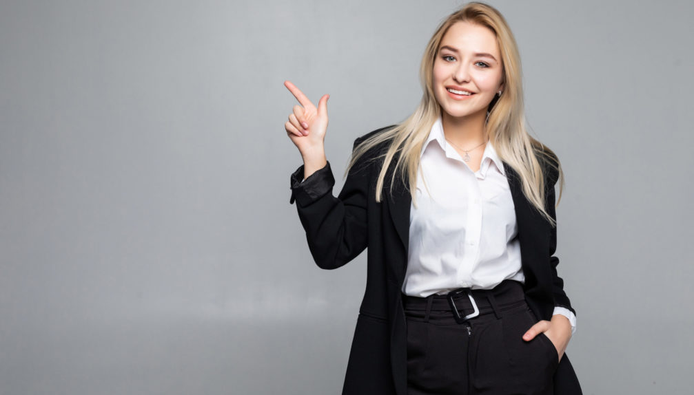 young-business-woman-pointing-finger-side-isolated-grey-wall