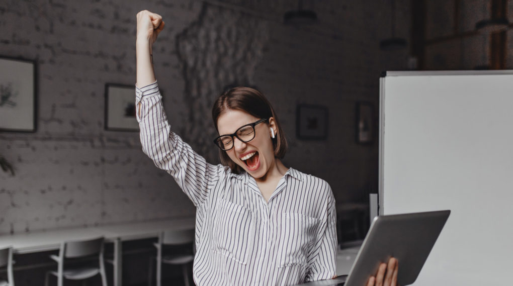 business-woman-with-laptop-hand-is-happy-with-success-portrait-woman-glasses-striped-blouse-enthusiastically-screaming-making-winning-gesture