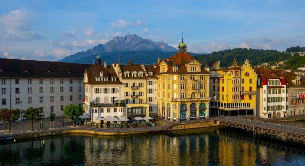 colorful-buildings-near-river-surrounded-by-mountains-lucerne-switzerland