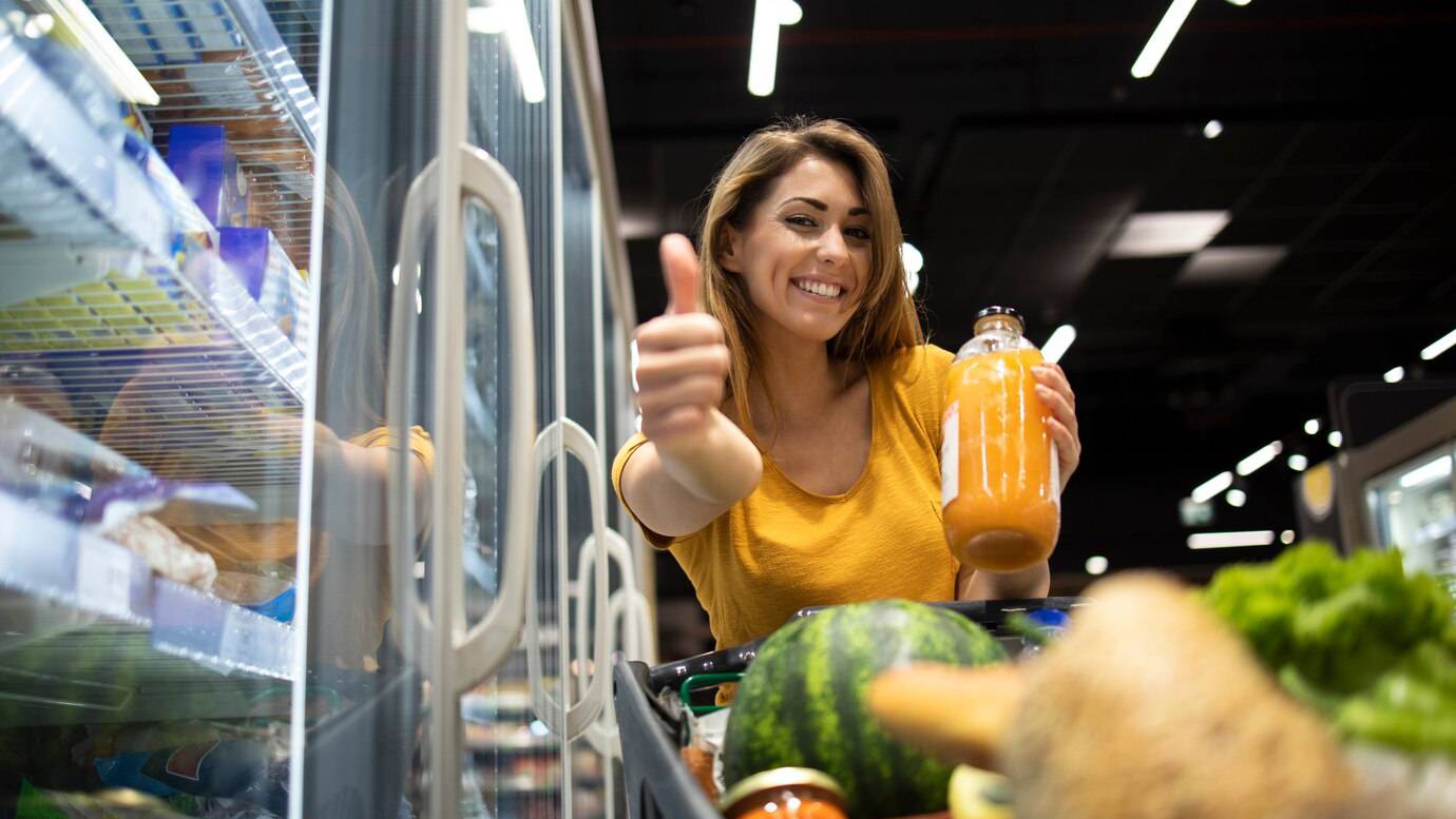 female-person-holding-orange-juice-in-grocery-store-and-showing-thumbs-up_342744-1135