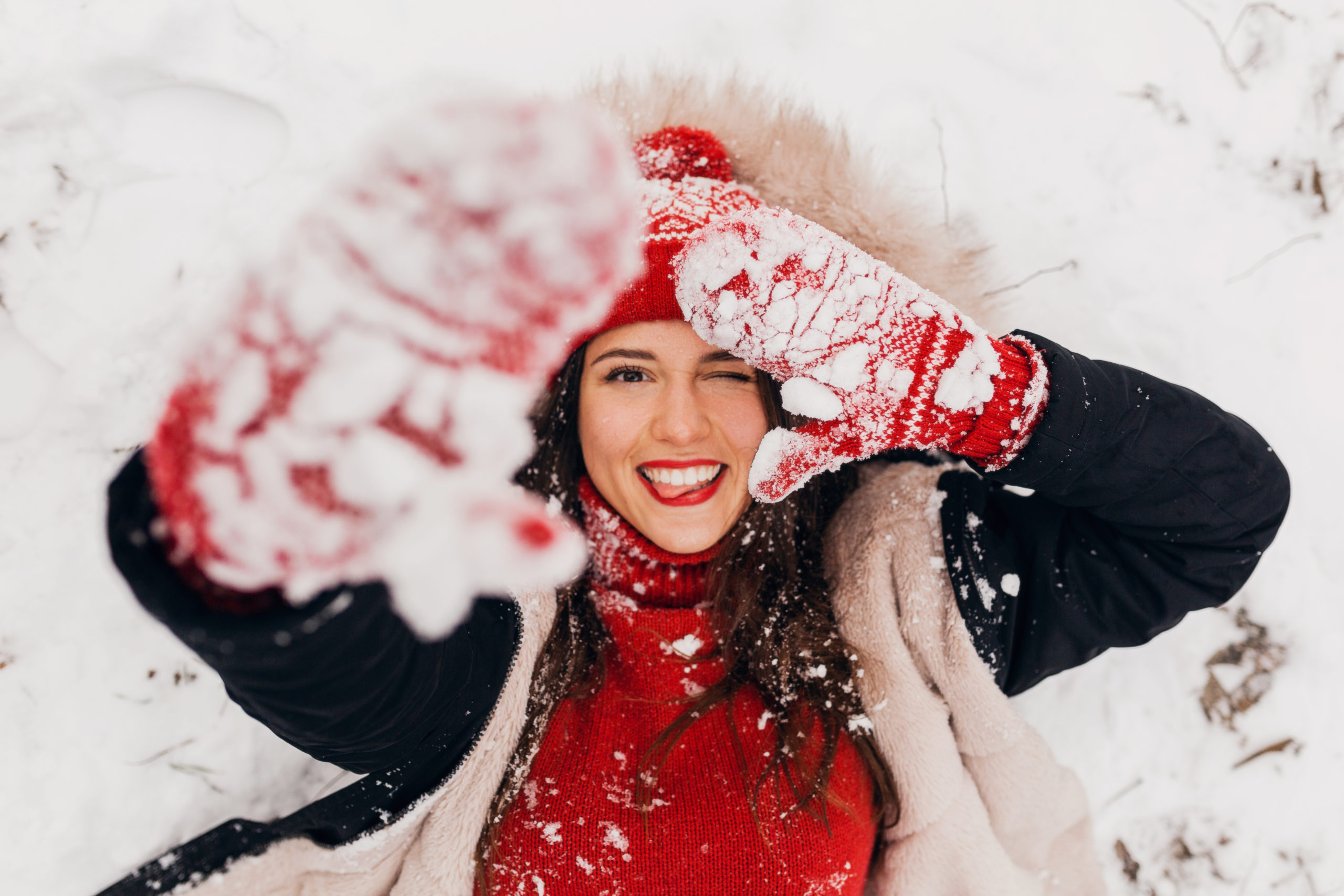 Девушка улыбается и лежит на снегу
