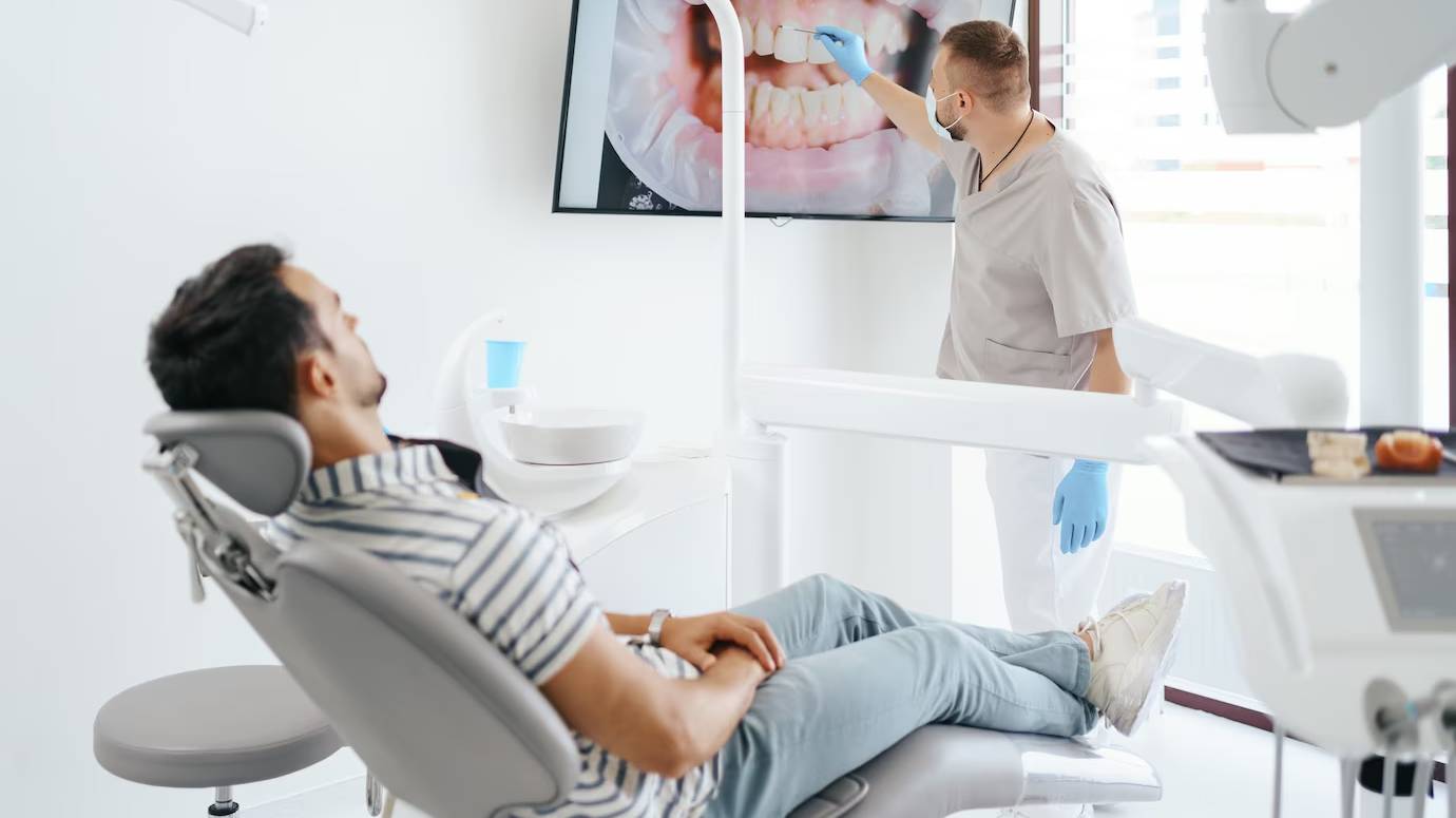 dentist-discussing-with-laying-patient-showing-image-his-teeth-screen_158595-7727