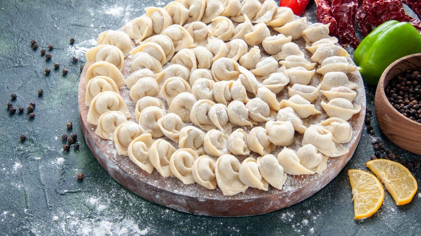 front-view-little-raw-dumplings-with-flour-vegetables-dark-surface_179666-44095 (1)
