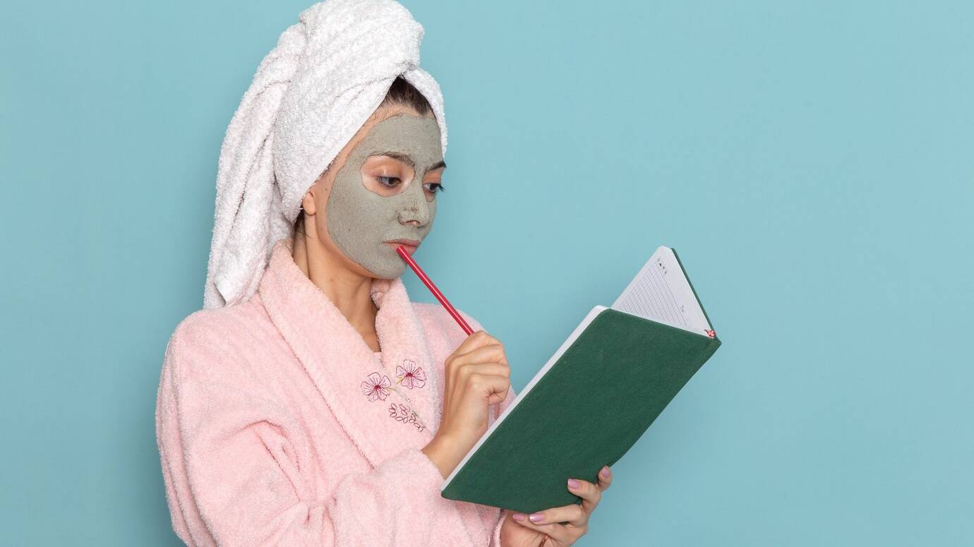 front-view-young-female-pink-bathrobe-after-shower-reading-copybook-blue-wall-beauty-water-cream-selfcare-shower-bathroom_140725-65434