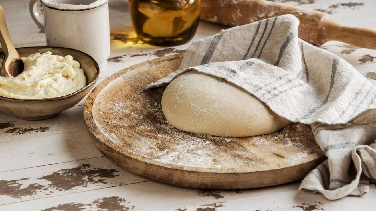 high-angle-pizza-dough-covered-with-cloth_23-2148753767