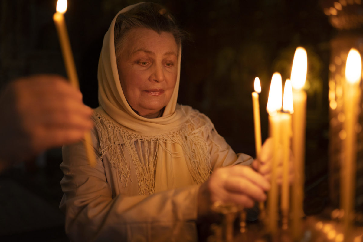 Женщина ставит свечку в церкви
