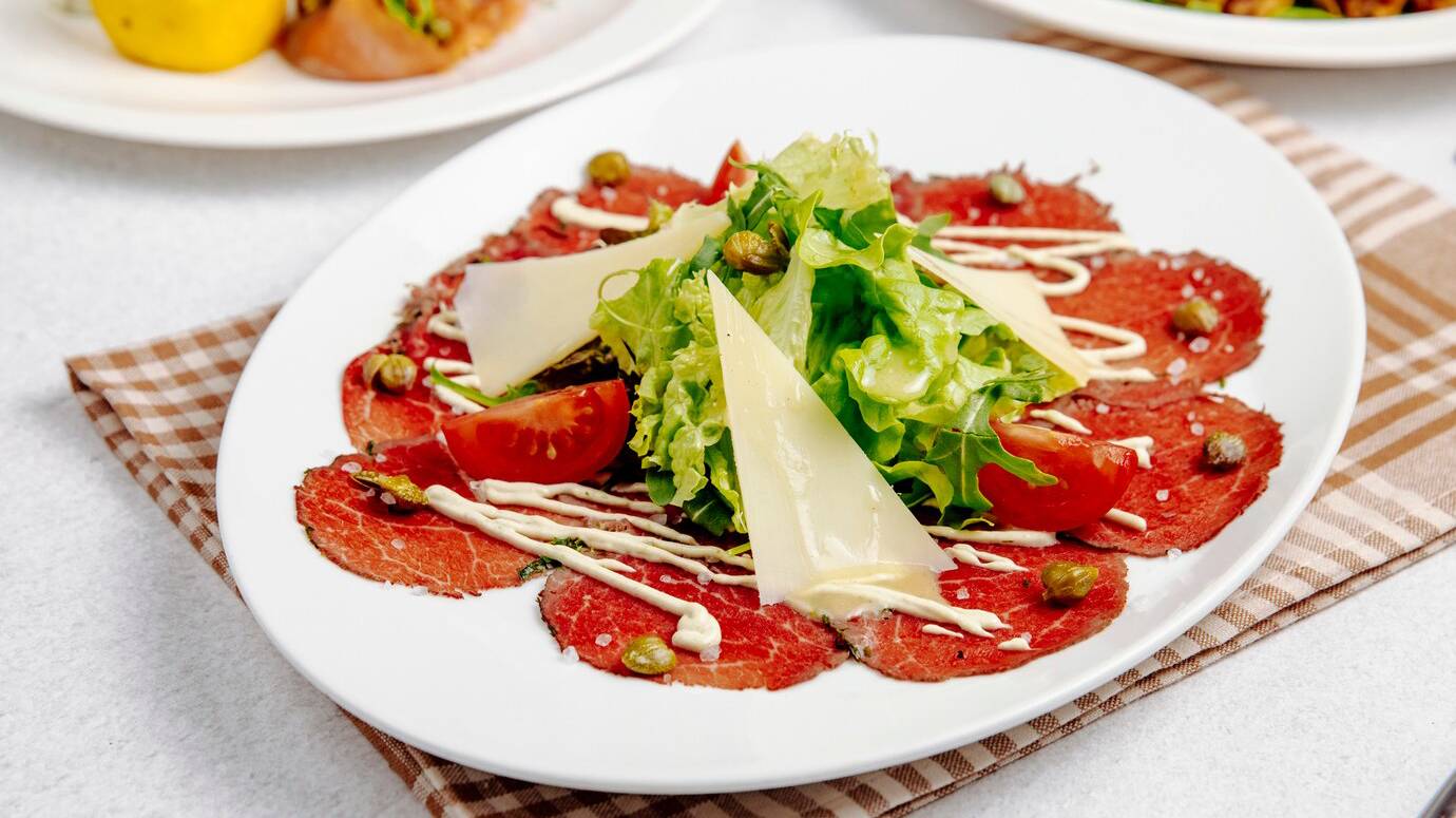 side-view-beef-carpaccio-with-parmesan-ruccola-tomatoes_141793-2671