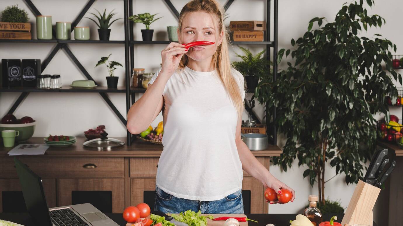 young-woman-standing-kitchen-smelling-red-chili_23-2147917760