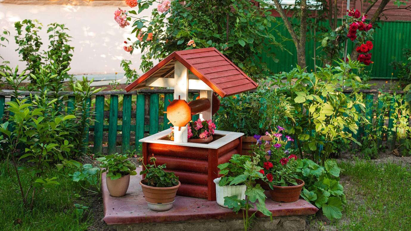 stock-photo-small-garden-backyard-fake-well-with-potted-flowers_132075-5927