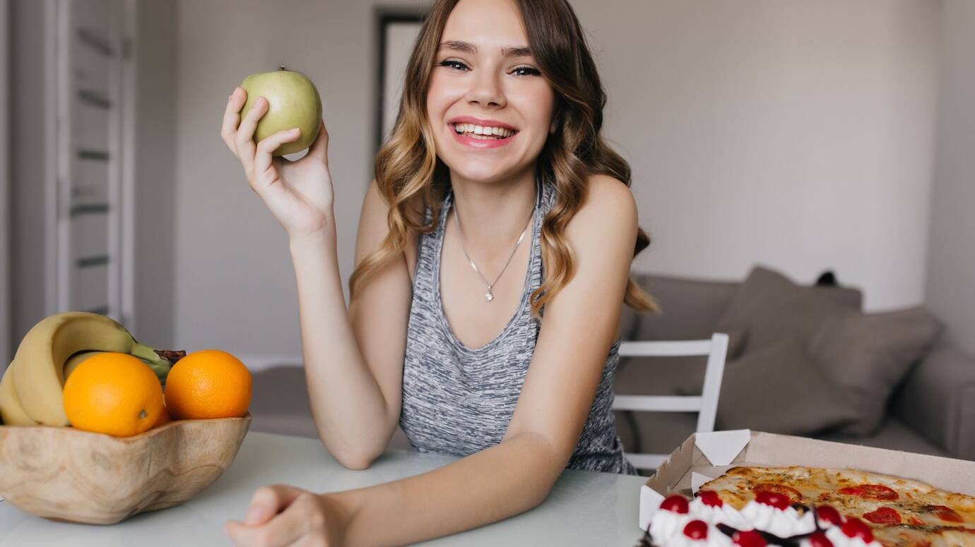 ecstatic-young-lady-having-fun-breakfast-with-green-apples-oranges-indoor-photo-positive-caucasian-girl-eating-fruits-cake_197531-9712