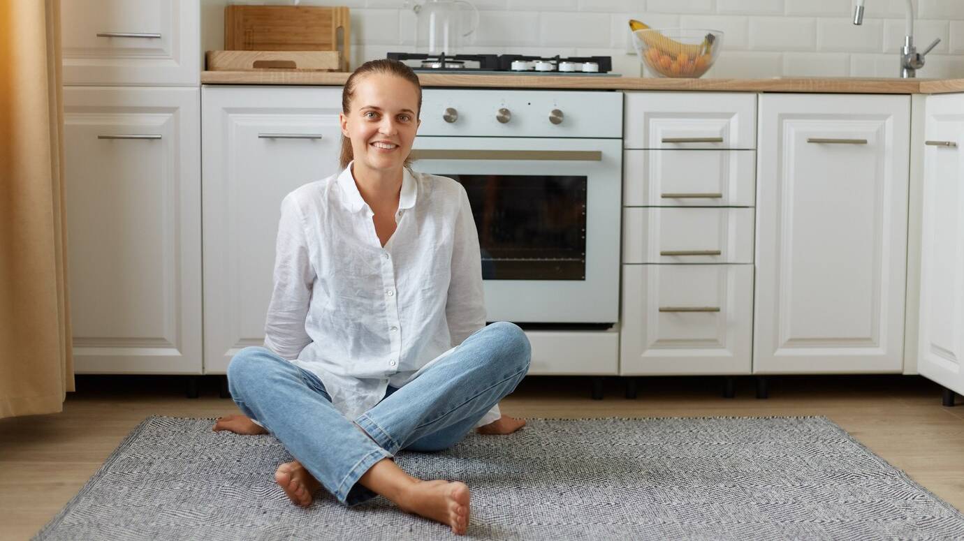 portrait-happy-beautiful-woman-posing-indoor-looking-camera-while-sitting-kitchen-floor-home-girl-with-ponytail-wearing-jeans-white-shirt_176532-15005