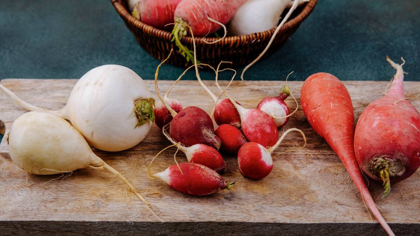 top-view-fresh-white-pinkish-red-root-vegetable-beetroots-wooden-kitchen-board-with-radishes-green-surface_141793-81130