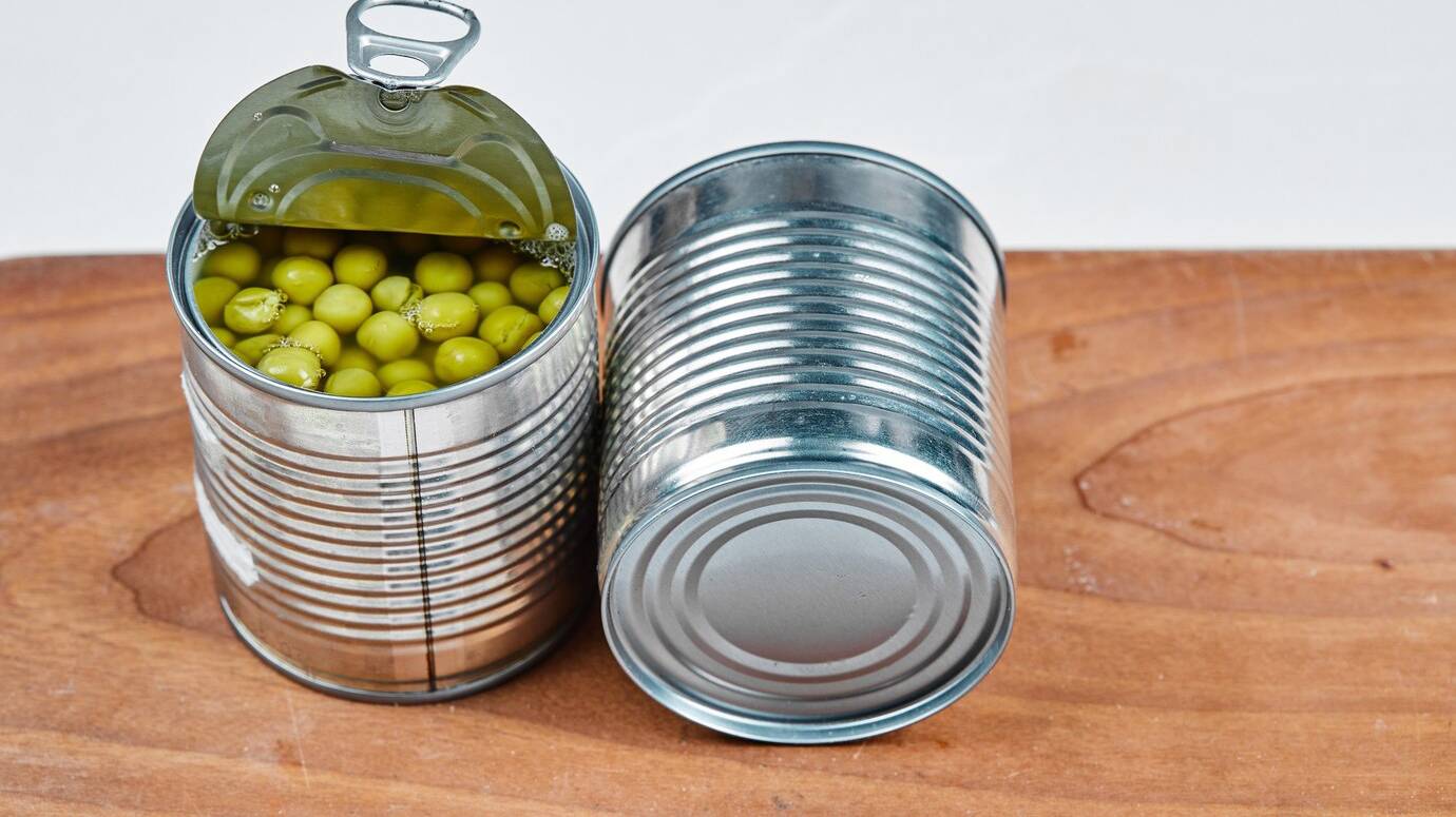 two-cans-boiled-green-peas-wooden-board_114579-24385