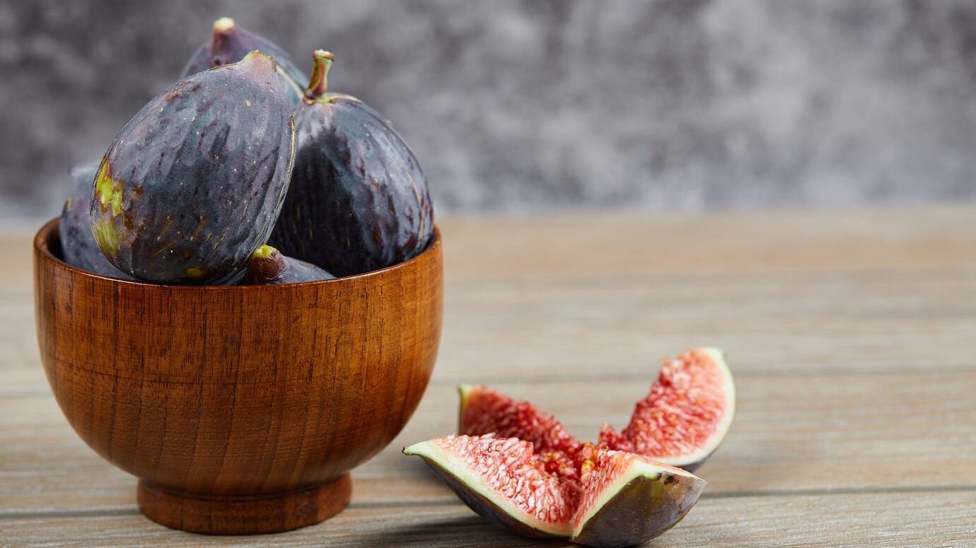 front-view-bowl-black-figs-slices-figs-wooden-table-high-quality-photo_114579-44253