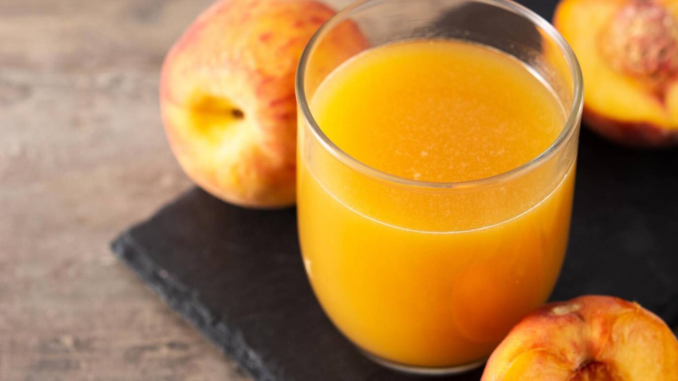 natural-peach-juice-glass-wooden-table_123827-22500