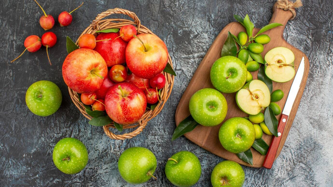 top-view-from-afar-apples-board-appetizing-green-apples-knife-basket-fruits_140725-78833 (1)