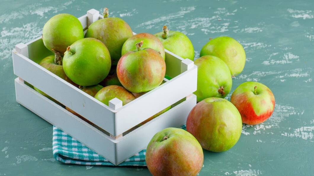 apples-wooden-box-plaster-picnic-cloth-background-high-angle-view_176474-9576