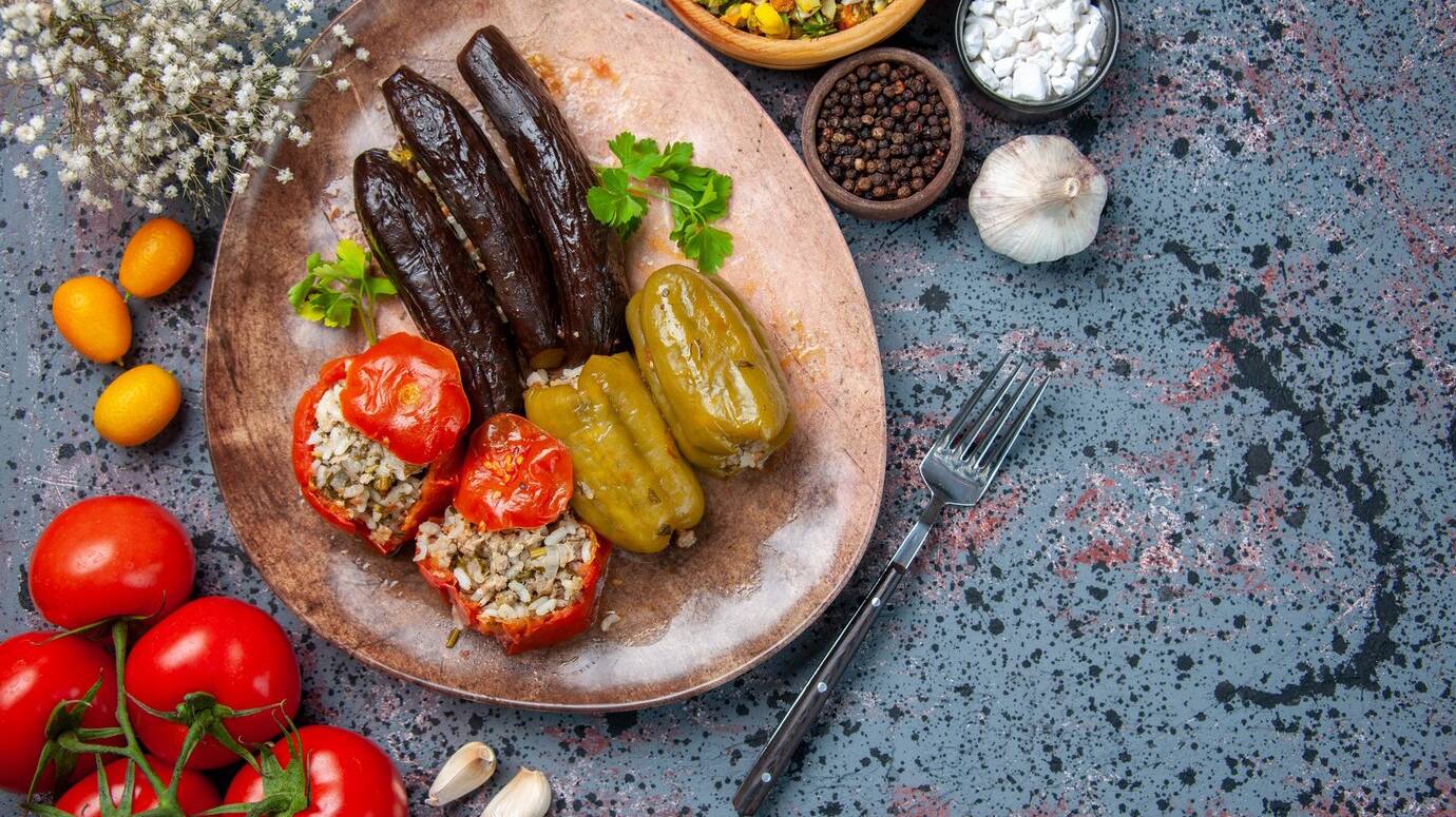 top-view-eggplant-dolma-with-cooked-tomatoes-bell-peppers-filled-with-ground-meat-inside-plate-dish-food-meal-colors_179666-17287