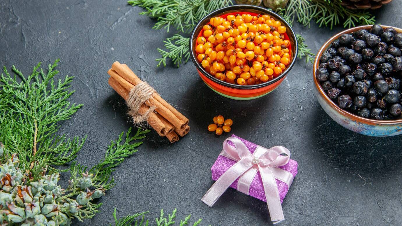 bottom-view-black-currant-sea-buckthorn-bowls-pine-branches-pinecones-dark-surface_140725-102606