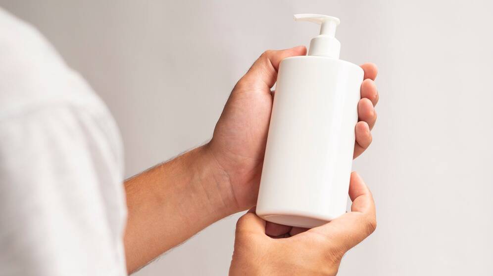 close-up-lotion-bottle-mock-up-holding-by-hands_23-2148295768