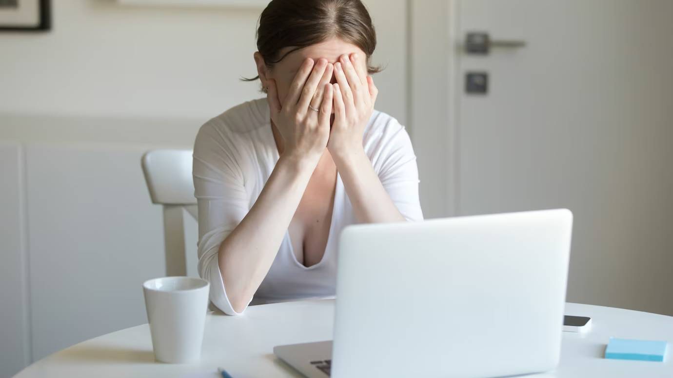 portrait-woman-desk-with-laptop-hands-closing-face_1163-2122