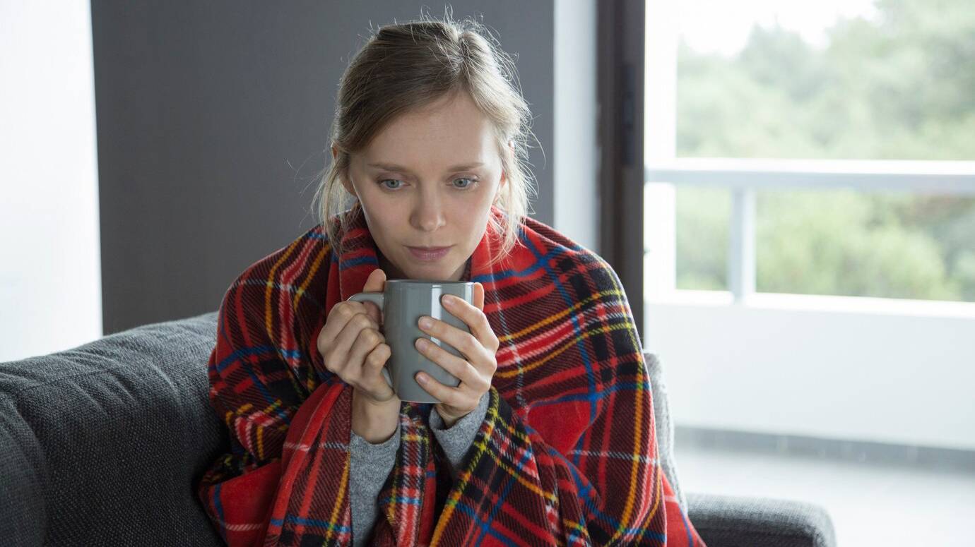 sick-woman-with-plaid-holding-cup-hands-looking-down_1262-18660