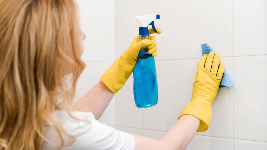 side-view-woman-cleaning-shower-wall_23-2148465057