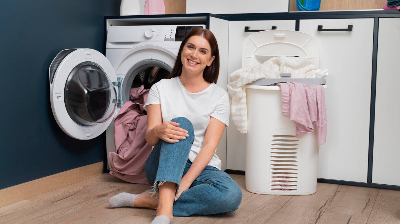 woman-sitting-washing-machine-with-basket-full-clothes_23-2149117084