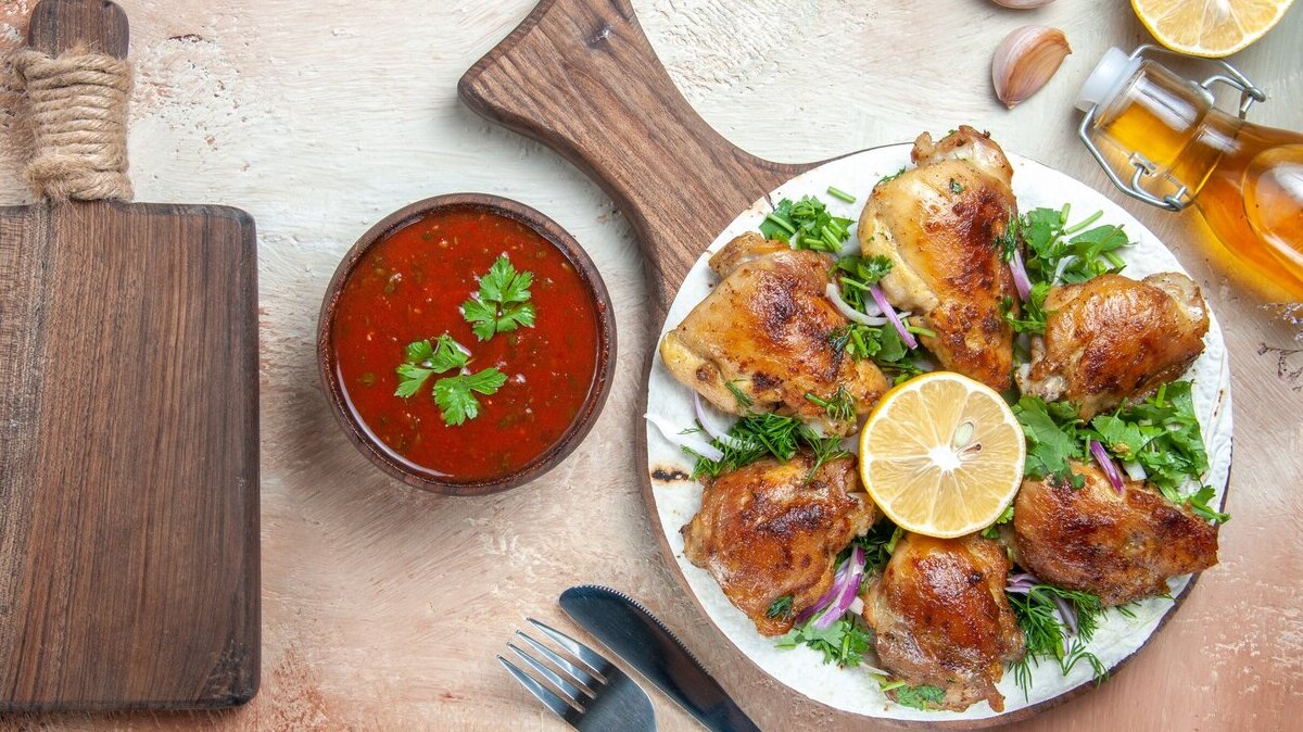 top-view-chicken-chicken-with-lemon-herbs-board-oil-fork-knife-cutting-board_140725-73668