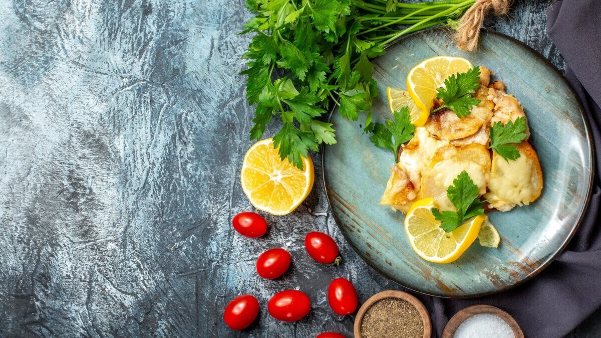 top-view-chicken-with-cheese-plate-bunch-parsley-lemon-cherry-tomatoes-spices-bowls-grey-table-with-copy-place_140725-85348