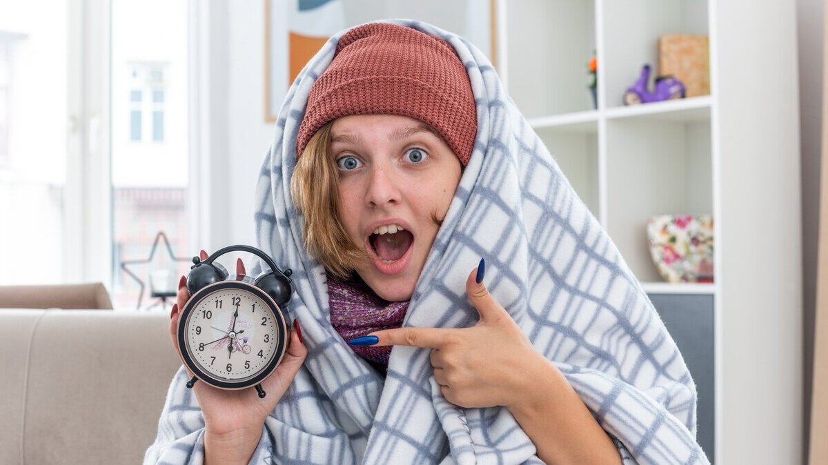 unhealthy-young-woman-hat-wrapped-blanket-holding-alarm-clock-surprsied-sitting-couch-light-living-room_141793-101912 unhealthy-young-woman-hat-wrapped-blanket-holding-alarm-clock-surprsied-sitting-couch-light-living-room_141793-101912