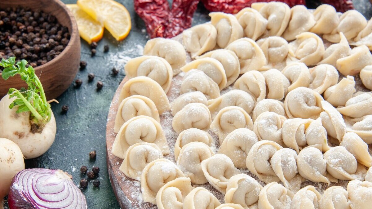 пельмени сырые пельмени на блюде рядом с овощами