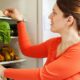 женщина складывает продукты в холодильник