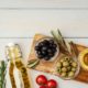 оливки и маслины лежат на столе рядом с оливковым маслом