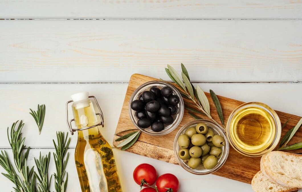 полезные продукты оливки и маслины лежат на столе рядом с оливковым маслом