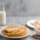 тонкие блинчики, бутылка молока и варенье на столе