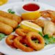 креветки и кальмары в клярк на тарелке с лимоном и томатным соусом